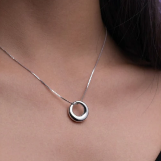 Collana da donna in acciaio inossidabile con catenella a maglie sottili. Il pendente centrale è sagomato a forma dell'iconico pugnale di Cesare Paciotti; la parte frontale del ciondolo, inclusa l'impugnatura e la lama, è interamente rivestita da un fitto pavé di piccoli zirconi bianchi brillanti che risaltano sulla struttura in metallo lucido.